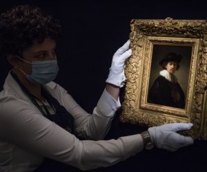 epa08563615 A worker poses with 'Self-portrait, wearing a ruff and black hat' by Dutch artist Rembrandt Van Rijn at the 'Rembrandt to Richter' art sale at Sotheby's auction house in London, Britain, 23 July 2020 (issued 24 July 2020). Works from Old Masters, Impressionist & Modern Art, Modern & Post-War British Art are on display at Sotheby's London ahead of a one-off auction on July 28.  EPA/NEIL HALL