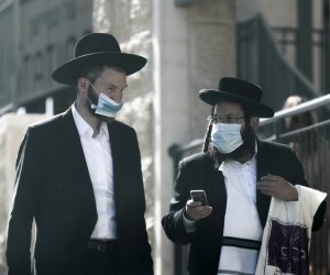 epa08549804 Ultra-Orthodox Jews wearing protective face masks pass at the blocked ultra-Orthodox neighborhood of Romama in Jerusalem, Israel,16 July 2020. The media report that Israeli government might announce lockdown in the country over the weekend as  Israel faces an increase in the number of people infected with the SARS-CoV-2 coronavirus. Israeli Police have increased enforcement significantly on government restrictions and closed some neighborhoods in various cities in order to prevent the spread of the SARS-CoV-2 coronavirus which causes the Covid-19 disease.  EPA/ATEF SAFADI