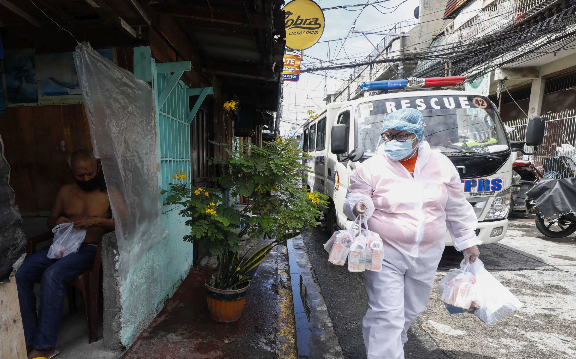 epa08581431 A city worker wearing a protective suit (R) goes around to handout free medicine and vitamins at a village under quarantine protocols in Caloocan City, Metro Manila, Philippines 03 August 2020. Philippine President Rodrigo Duterte approved a recommendation to impose stricter quarantine protocols from 04 to 18 August in Metro Manila and the nearby provinces of Laguna, Cavite, Rizal and Bulacan. The move came after pleas from medical professionals for tighter measures due to rising coronavirus disease (COVID-19) cases.  EPA/ROLEX DELA PENA