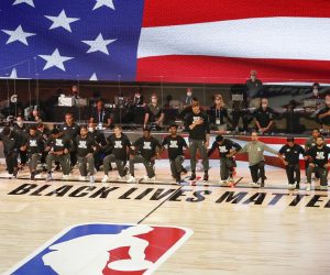 epa08582308 Members of the Toronto Raptors and the Miami Heat kneel during the National Anthem before the start of the NBA basketball game between the Toronto Raptors and the Miami Heat at the ESPN Wide World of Sports Complex in Kissimmee, Florida, USA, 03 August 2020. The NBA season has restarted at the Walt Disney World sports complex outside Orlando, Florida.  EPA/ERIK S. LESSER SHUTTERSTOCK OUT