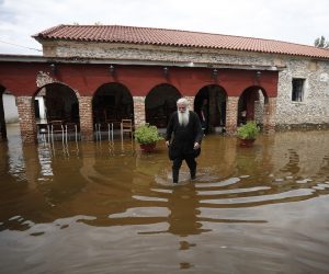 epa08589542 A Greek Orthodox priest walks in front of a flooded 18th century church in the village of Kavalari, Thessaloniki, Greece, 07 August 2020, after heavy rains hit the greater Langadas area in Greece. Rainstorms struck the region of Thessaloniki overnight 07 August and caused severe problems and damage, mostly in the Langadas region. The local meteo service recorded 78 mm of precipitation in approximately 3.5 hours and a total of 90 mm by early Friday, 07 August. On the third day since the weather front 'Thalia' arrived in Greece, the bad weather conditions will spread to a large part of the country with the only exception being the region of Thrace, the island of Evia and probably the island of Crete.  EPA/DIMITRIS TOSIDIS