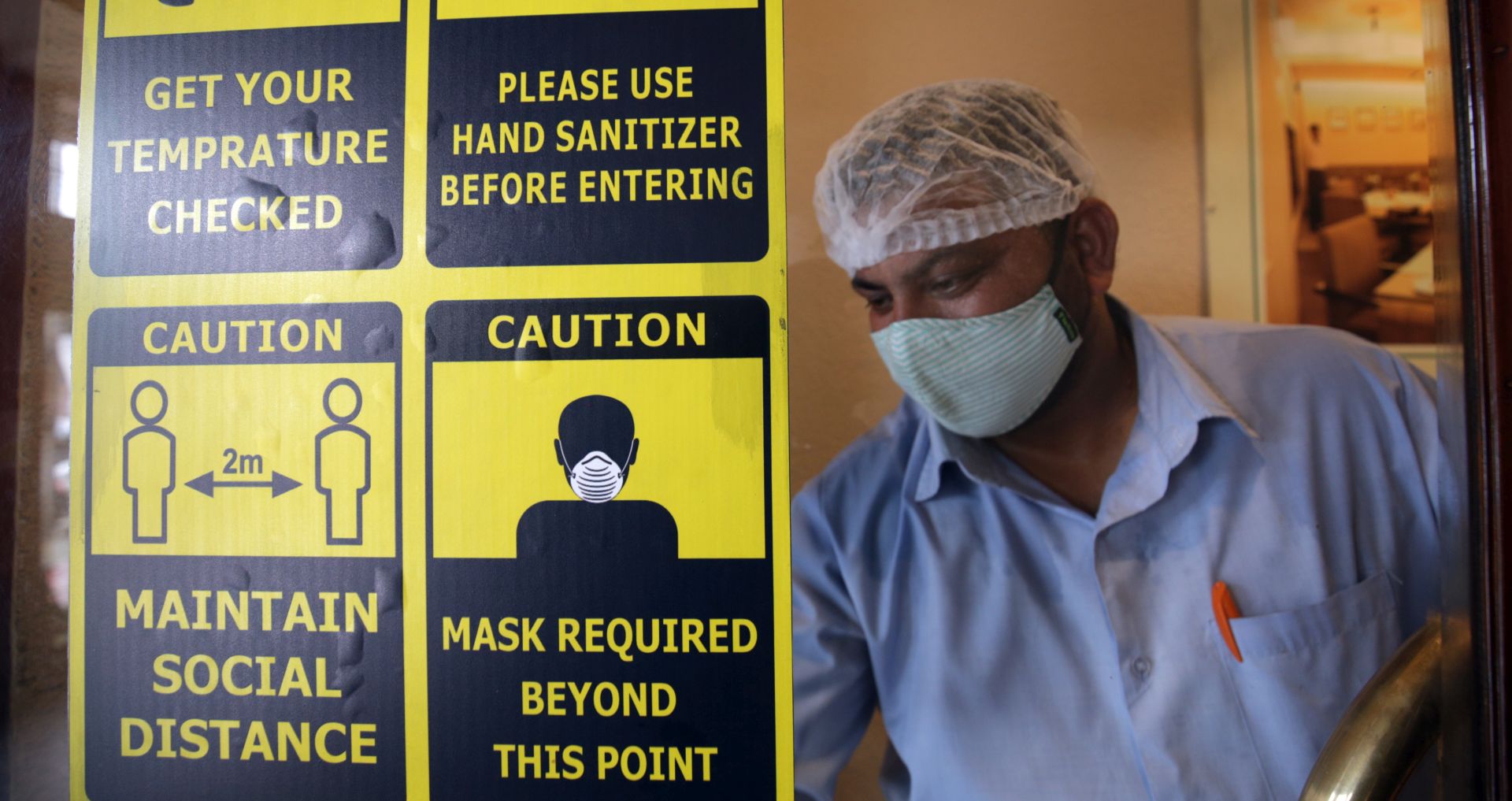 epa08624626 Signs for precautions against novel coronavirus which causes Covid19 disease are displayed on a door as a worker cleans its glass at the Astoria Food Pavilion restaurant, after easing some restrictions in wake of Covid19 pandemic, in Amritsar, India, 25 August 2020. According to new guidelines by the state government, the restaurants and food joints are allowed to remain open till half past six in the evening, with dine-in and take away facilities provided to the customers. Coronavirus related cases have crossed the three million mark in India.  EPA/RAMINDER PAL SINGH