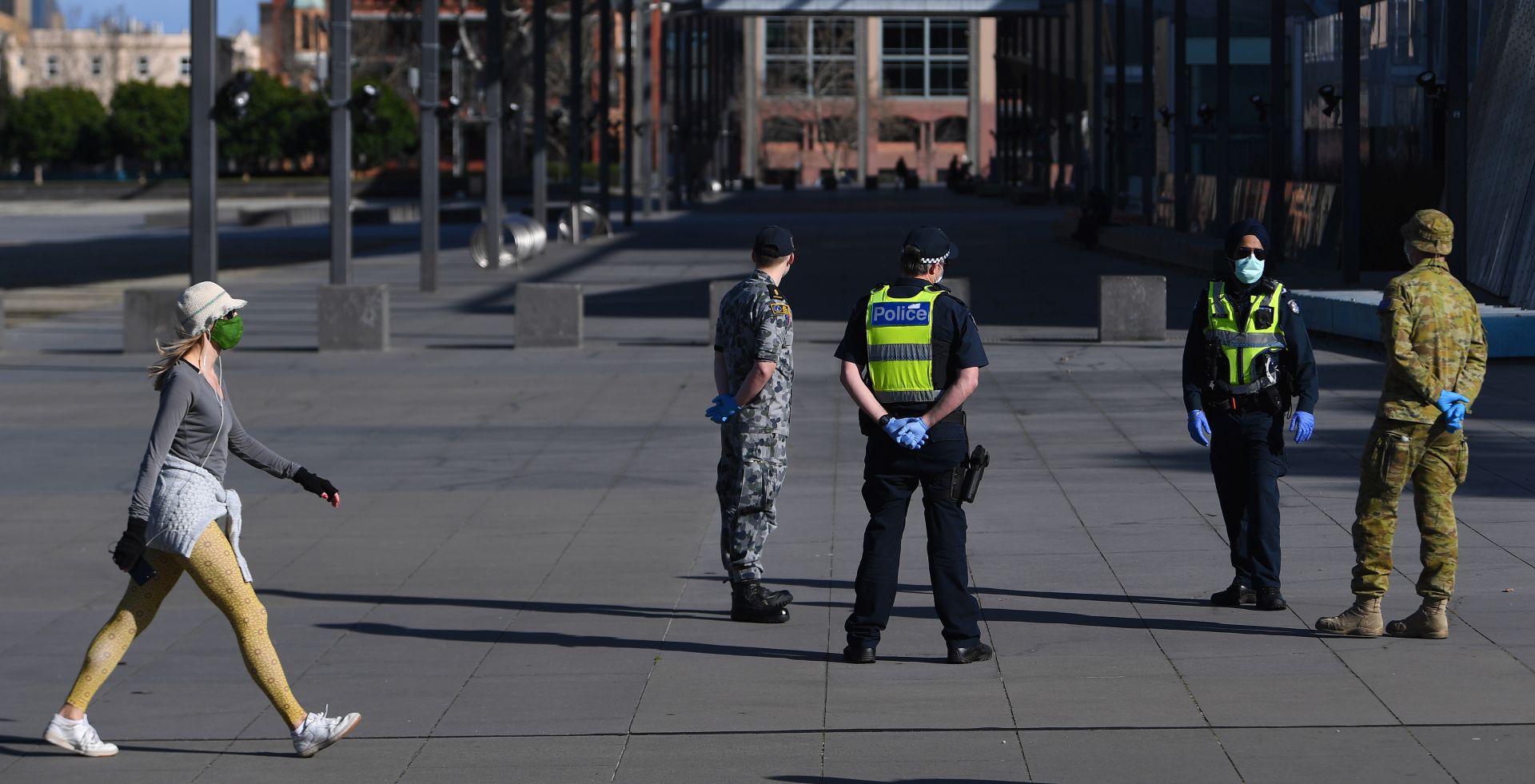 epa08615600 A person wearing a face mask walks past Victoria Police, Airforce and Australian  Defense Force (ADF) personnel outside of the Melbourne Museum in Melbourne, Victoria, Australia, 21 August 2020.  EPA/JAMES ROSS AUSTRALIA AND NEW ZEALAND OUT