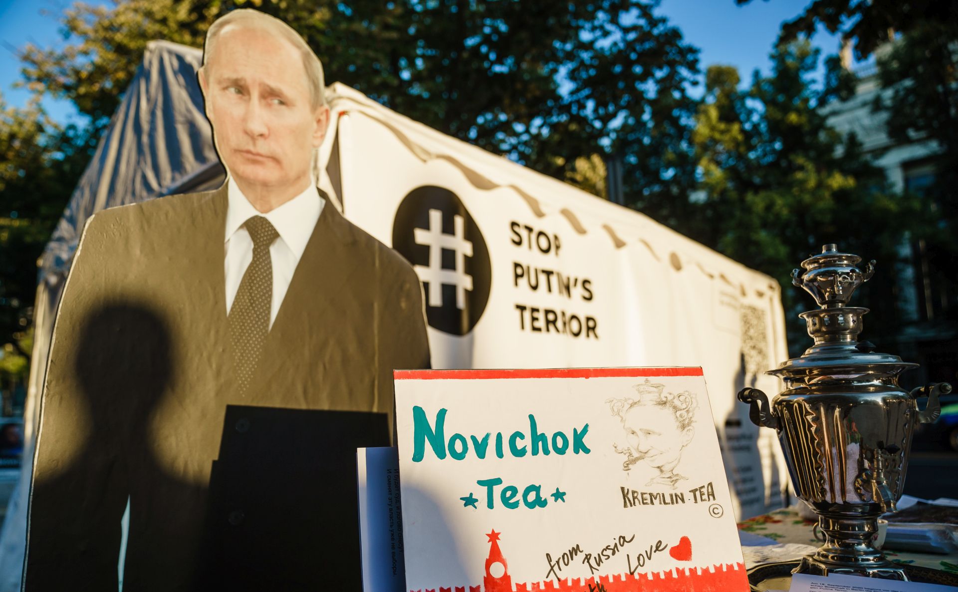 epa08679342 A staged protest in front of the Russian embassy shows a picture of Russian President Vladimir Putin (C), Russian opposition activist Alexei Navalny (L) and a Russian teapot samovar with a note reading 'Novichok tea', 'Kremlin tea' and 'from Russia with love', in Berlin, Germany, 16 September 2020. Navalny is receiving treatment at the Charite hospital in Berlin since 22 August 2020 after being poisoned with a nerve agent from the Novichok group.  EPA/CLEMENS BILAN