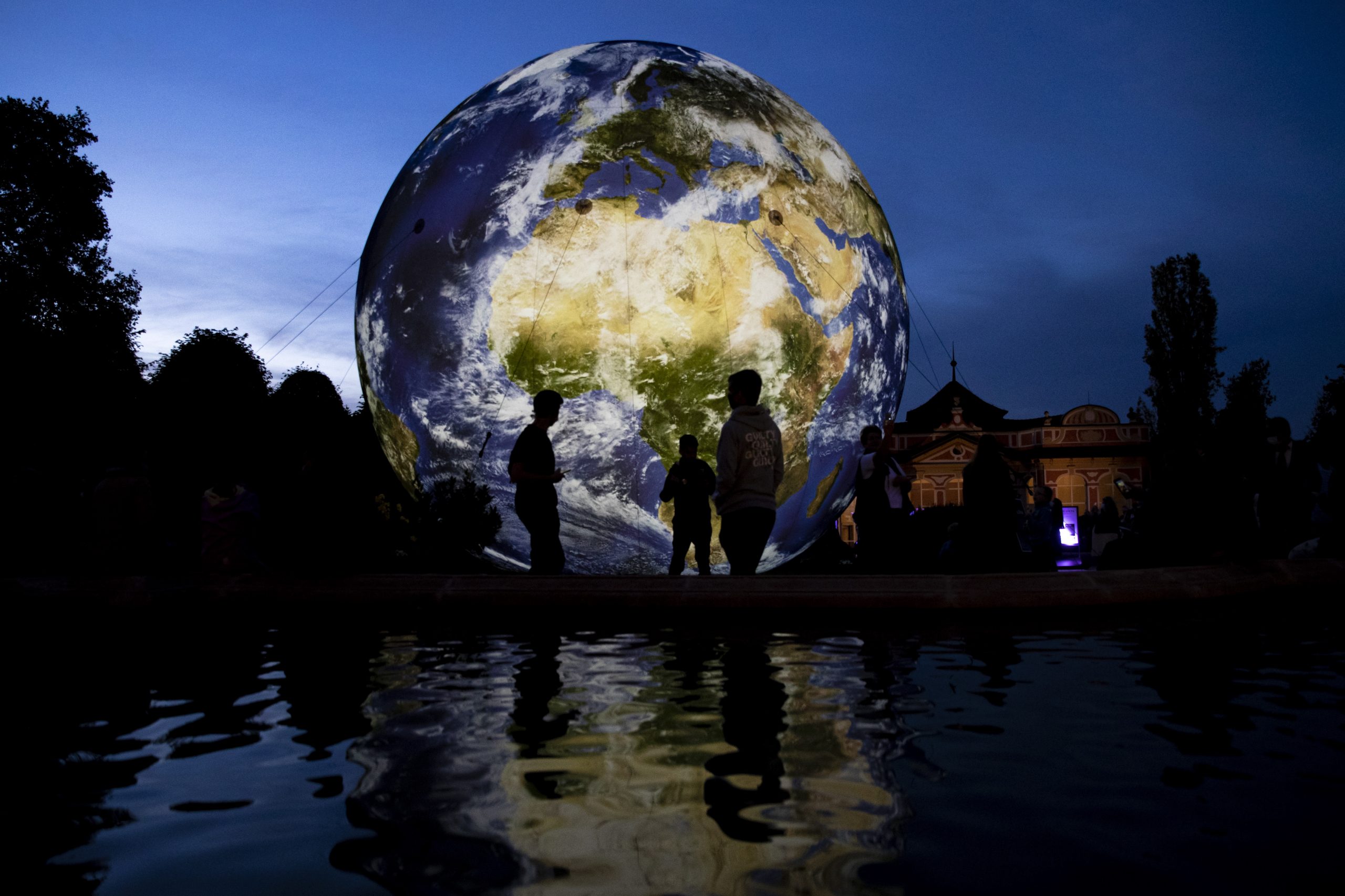 epa08682667 People stand in front of the giant inflatable model of the Earth during the European Sustainable Development Week, as well on World Clean Up day, at the garden of Czech Ministry of Foreign Affairs in Prague, Czech Republic, 19 September 2020. Through this event, the Czech Foreign Ministry wants to present a country as active in matters of sustainability and climate.  EPA/MARTIN DIVISEK
