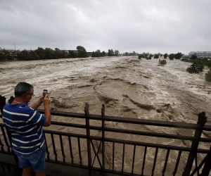 epa08716000 A man takes a picture of the flooded Var river during a powerful storm named Alex on the French Riviera near Nice, France, 02 October 2020.  EPA/SEBASTIEN NOGIER