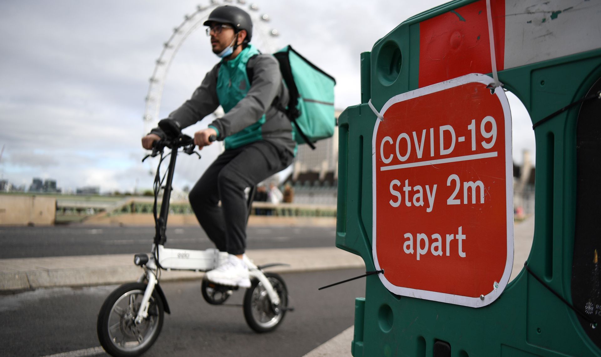 epa08746914 A food courier cycles over Westminster Bridge in London, Britain, 15 October 2020. According to news reports the UK government is set to impose further restrictions on London, as Covid -19 infections continue to rise.  According to recent data from the Office for National Statistics (ONS) Covid-19 deaths in England have risen four fold over the last month.  EPA/ANDY RAIN