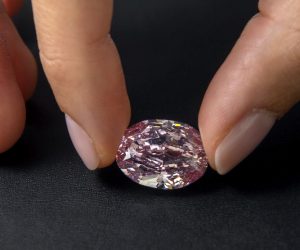 epa08802991 A Sotheby's employee poses with 'The Spirit of the Rose' vivid purple-pink diamond weighing 14.83-carat, during a preview at Sotheby's in Geneva, Switzerland, 06 November 2020. The diamond will be offered for sale at an auction in Geneva on 11 November.  EPA/SALVATORE DI NOLFI
