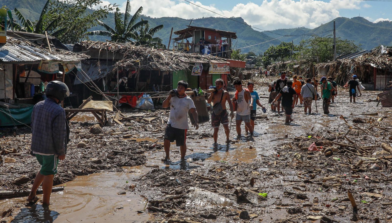 epa08816993 Residents carry salvaged belongings along a road covered in mud and debris in the aftermath of Typhoon Vamco in Rodriguez, Rizal, east of Manila, Philippines, 13 November 2020. According to reports the death toll rose to at least 26 as Typhoon Vamco caused floods in Metro Manila, neighboring provinces and parts of the Bicol region after making landfall in the southern Luzon region.  EPA/MARK R. CRISTINO