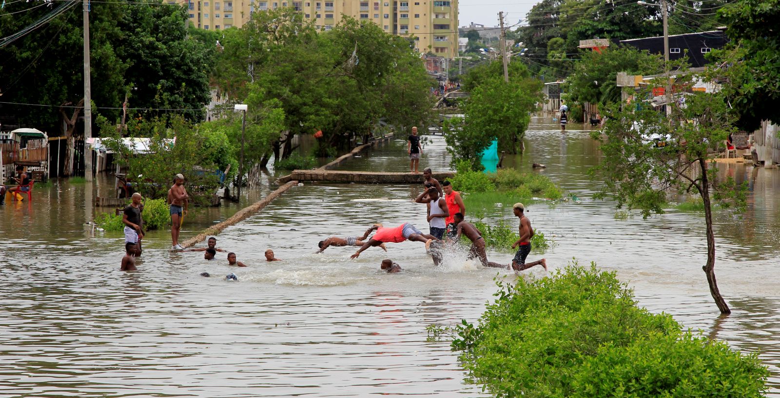 epa08822732 Residents of a low-income neighborhood bathe in a flooded street due to the rains caused by Hurricane Iota, in Cartagena, Colombia, 15 November 2020. The floods and landslides caused by the Iota rains have led to an emergency in Cartagena de Indias, which has had to decree public calamity. The city reports 31,555 families affected and 33 neighborhoods flooded. Iota, which this morning intensified to become a hurricane, is approaching this Sunday towards Nicaragua and Honduras, countries recently hit by another cyclone.  EPA/RICARDO MALDONADO ROZO