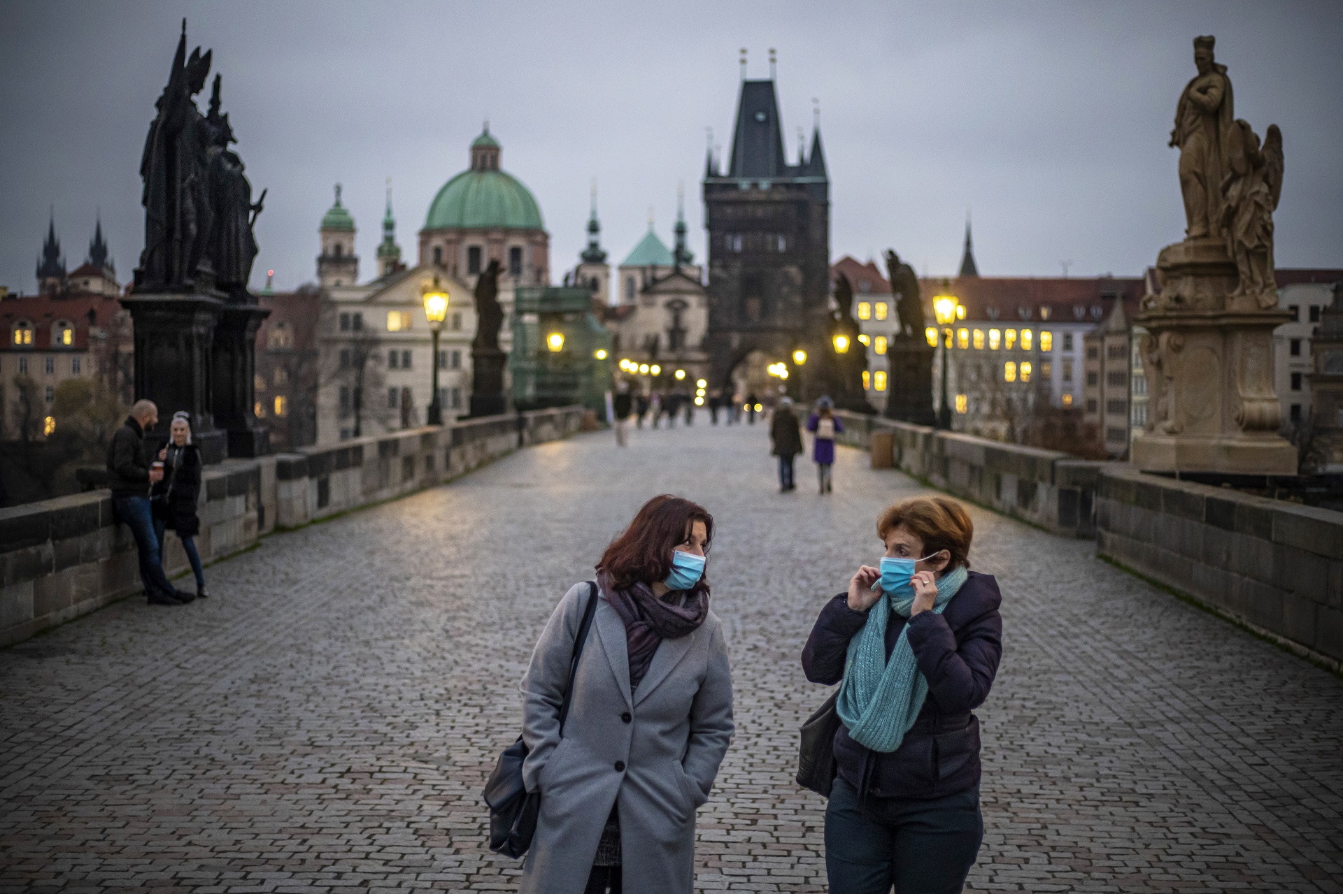 epa08810147 Women wearing protective face masks walk on Charles Bridge at dusk in Prague, Czech Republic, 09 November 2020. The Czech Republic has seen a declining trend in COVID-19 positive tested people after authorities imposed measures at the end of October to limit the increase in cases.  EPA/MARTIN DIVISEK