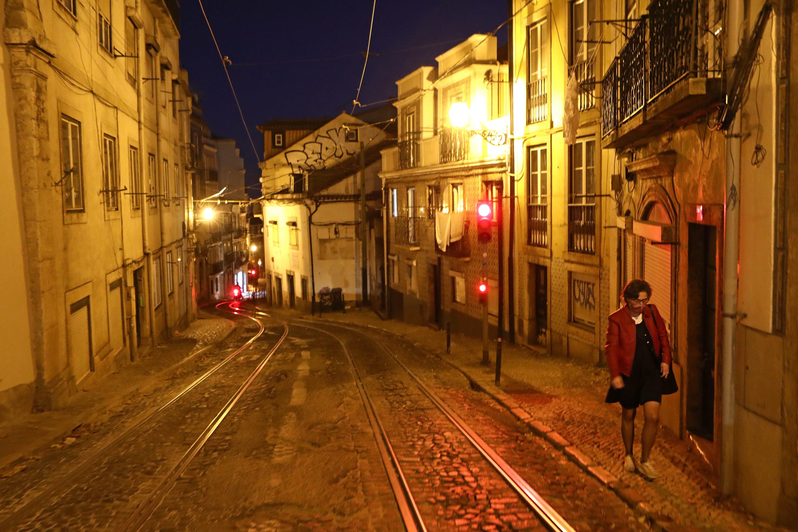 epa08835284 A woman walks in a deserted street during the lockdown of the state of emergency, as part of the measures to contain covid-19, in Lisbon, late 21 November 2020. With 213 municipalities at risk in Portugal, the Council of Ministers decreed over the weekend the closure of all shops and restaurants from 1 pm to 8 am the following day, in addition to the mandatory confinement for the entire population of these municipalities from 1 pm.  EPA/ANTONIO PEDRO SANTOS