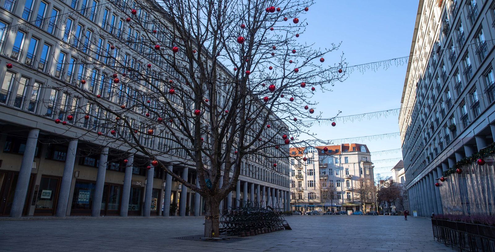 epa08893529 Outdoor chairs and tables are locked next to a tree decorated with Christmas balls at the Walter-Benjamin-Platz in Berlin, Germany, 19 December 2020. As the number of cases of the COVID-19 disease caused by the SARS-CoV-2 coronavirus is still rising throughout Germany, the government has imposed a second hard lockdown with businesses closing from 16 December on until 10 January 2021.  EPA/HAYOUNG JEON