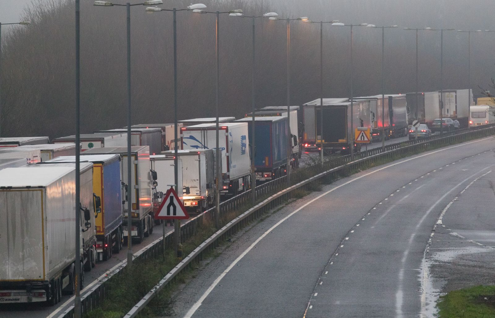 epa08900695 Lorries queue up on the A2 on the outskirts of Dover, Britain, 23 December 2020. France closed its border with the UK for 48 hours over concerns about the new coronavirus variant. Lorry drivers must now obtain negative coronavirus tests before they will be allowed to cross by sea and the Port of Dover remains closed to outbound traffic on the morning of 23 December 2020.  EPA/VICKIE FLORES