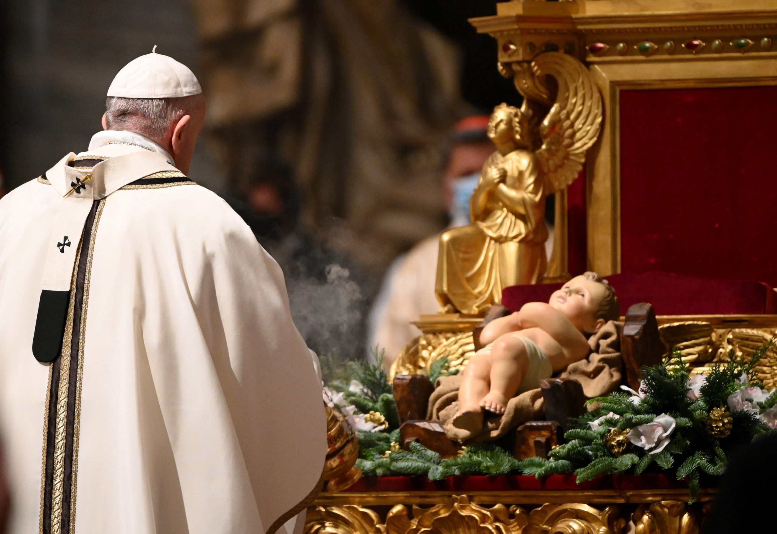 epa08902986 Pope Francis kisses a figurine of baby Jesus during a Christmas Eve mass to mark the nativity of Jesus Christ, at St Peter's basilica in the Vatican, 24 December 2020.  EPA/VINCENZO PINTO / POOL