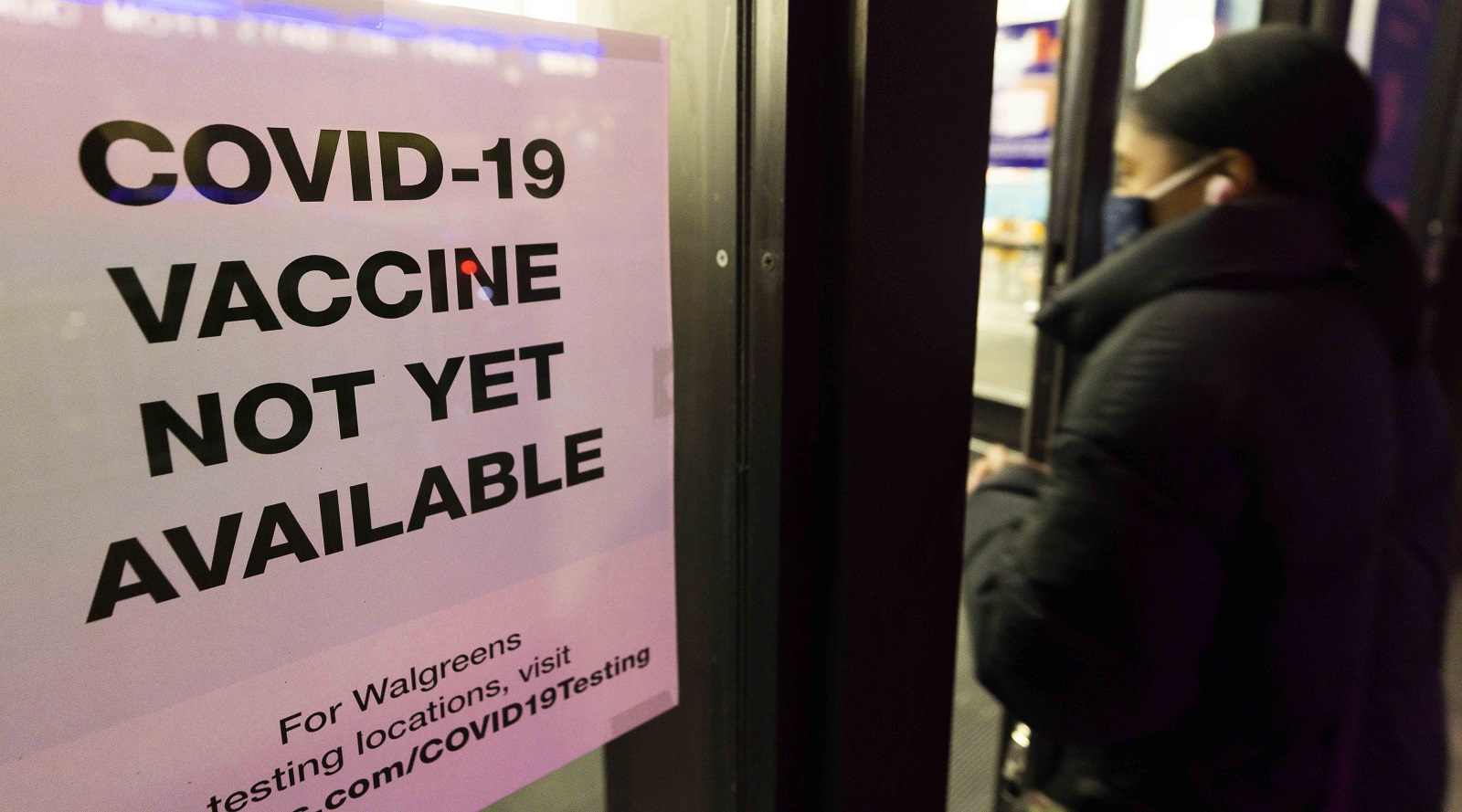 epa08856317 A person walks past sign informing customers about COVID-19 vaccine availability at a drug store in New York, USA, 01 December 2020.  EPA/JUSTIN LANE