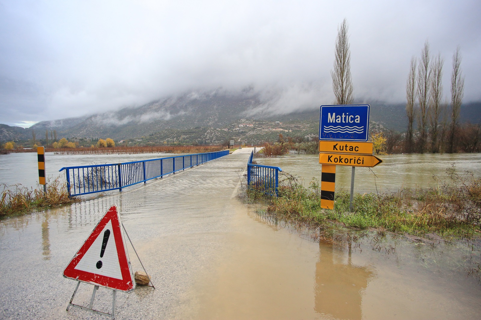Vrgorac, 05.12.2020. - Nakon obilnih kiša rijeka Matica se izlila iz toka i poplavio je dio ceste između Vrgorca i Ploča. U jutarnjim satima voda je poplavila Vinski most i promet od Vrgorca, s izlaza autoceste na čvoru Vrgorac, prema Pločama i Dubrovniku se odvija otežano.
Cestarske službe su stavile znakove upozorenja na nekoliko mjesta, ali voda nadire i vjerojatno će doći do većeg zastoja u prometu.
Cesta od sela Kutac prema Vinskom mostu također je dijelom pod vodom, pa se vozači koji putuju prema Pločama upozoravaju na oprez. foto HINA/ Jure DIVIĆ/ ml