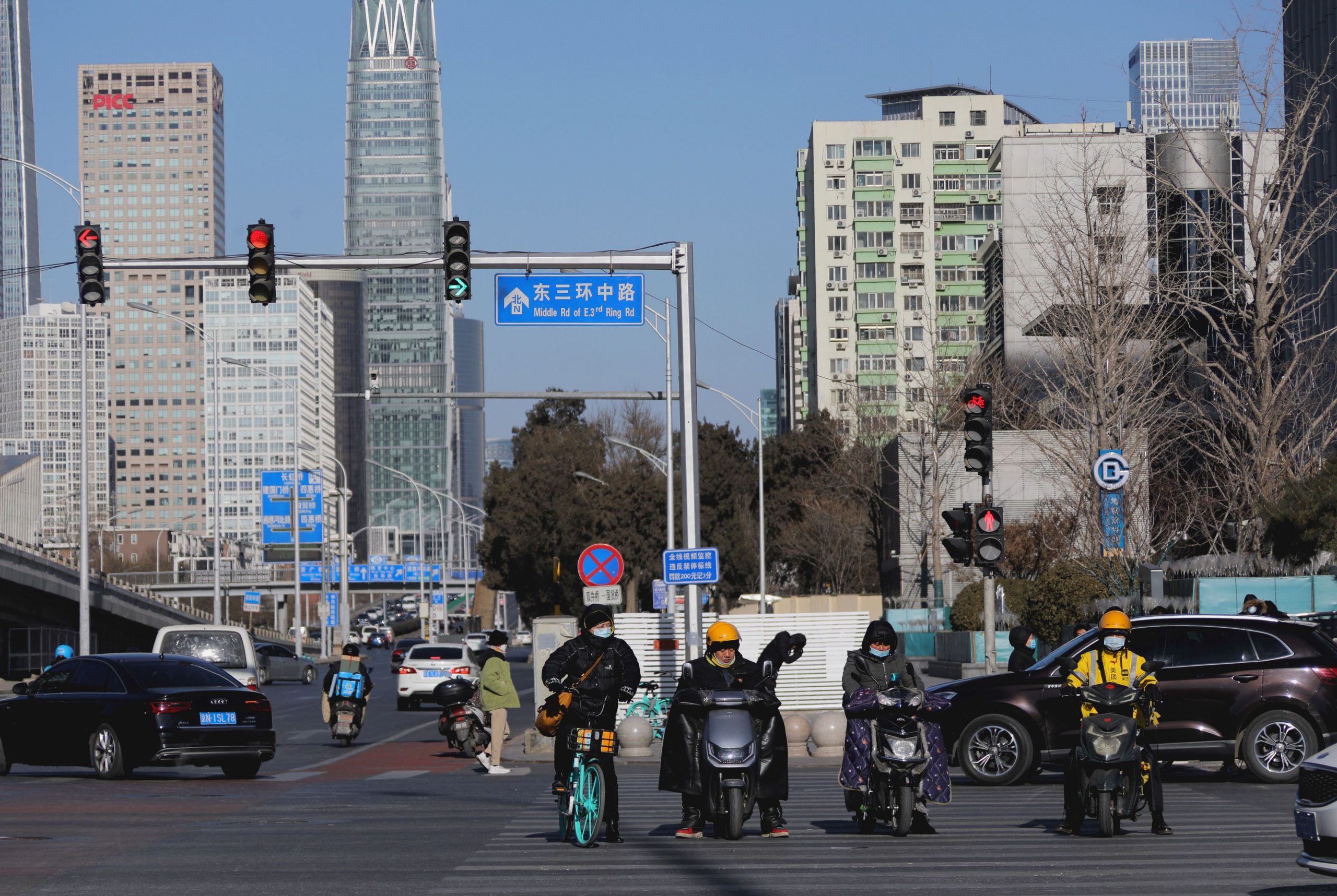 epa08910734 People wearing protective face masks ride their scooters at a street in Beijing, China, 30 December 2020, amid the coronavirus disease (COVID-19) pandemic. China reported 24 new cases of COVID-19 on the mainland on 29 December 2020.  EPA/WU HONG