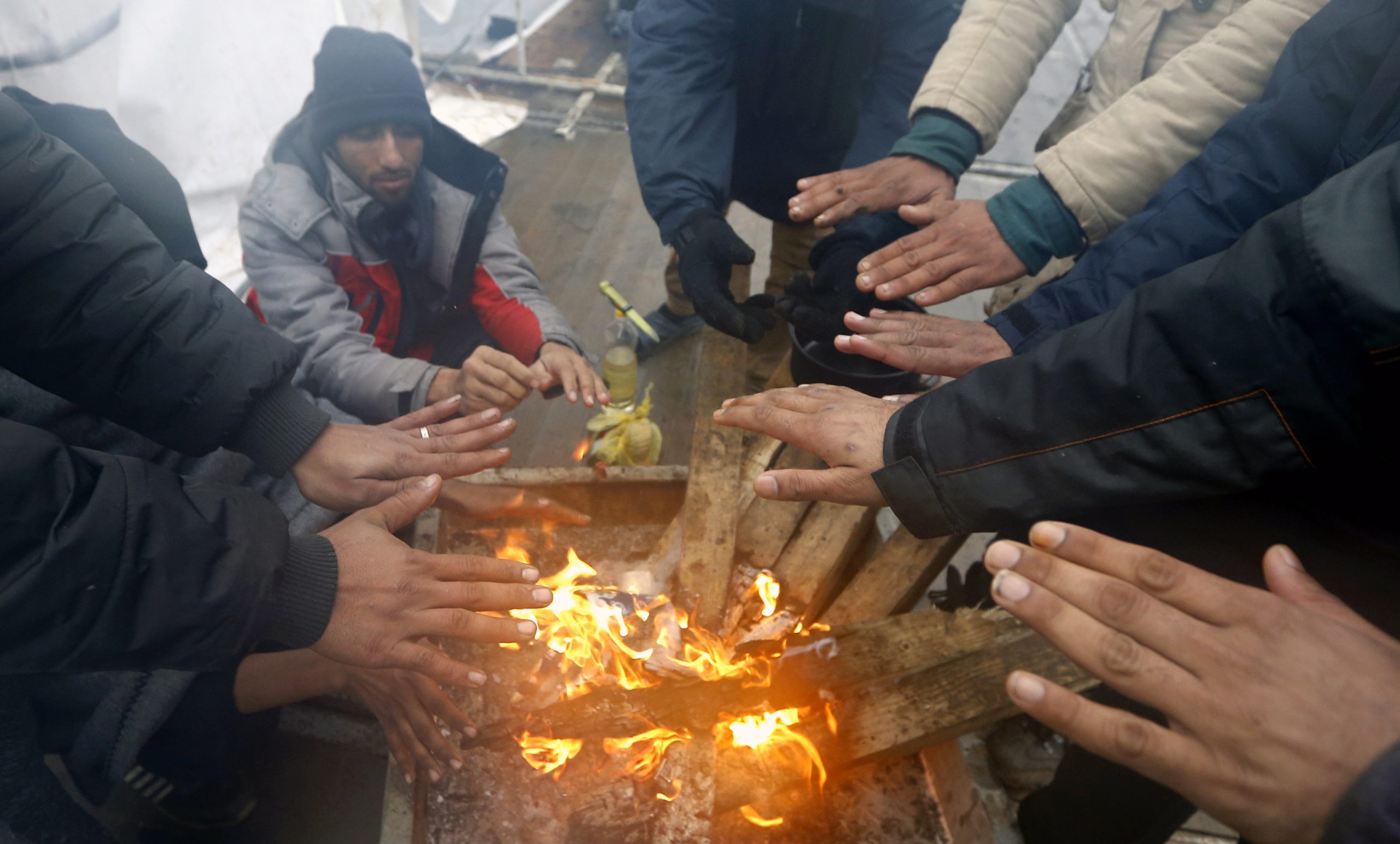 epaselect epa08914523 Migrants warm themselves by a campfire during a winter day at the Lipa refugee camp outside Bihac, Bosnia and Herzegovina, 01 January 2021. Some thousand refugees at the camp were scheduled to be relocated from the burnt-down tent camp on 31 December, yet were returned to Lipa camp. A fire on 23 December destroyed most of the camp near the city of Bihac, which has already been sharply criticized by international authorities and aid groups as unsuitable for accommodating refugees and migrants.  EPA/FEHIM DEMIR