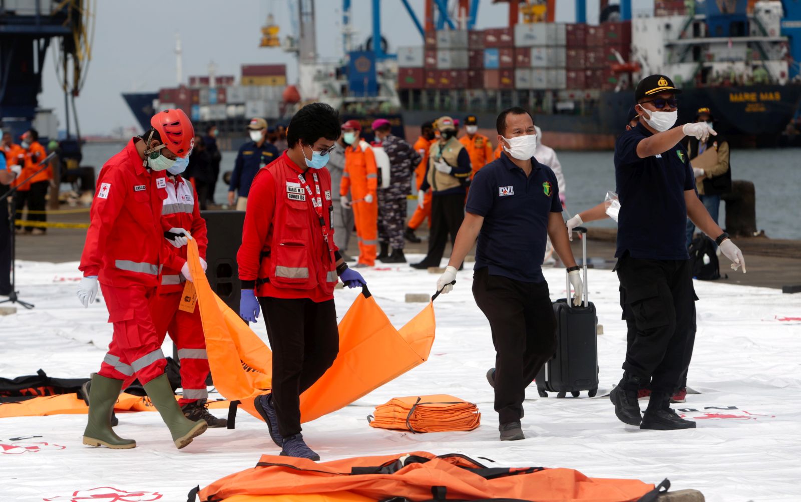 epa08929635 Indonesian rescuers and Disaster Victim Identification (DVI) police officers carry a body bag at Tanjung Priok port in Jakarta, Indonesia, 10 January 2021. Contact to Sriwijaya Air flight SJ182 was lost on 09 January 2021 shortly after the aircraft took off from Jakarta International Airport while en route to Pontianak in West Kalimantan province.  EPA/ADI WEDA