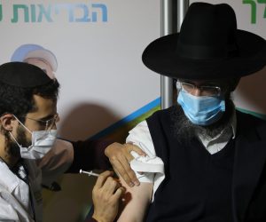 epa08937701 An ultra-orthodox Jewish man receives a coronavirus COVID-19 pandemic vaccine by a male nurse in Jerusalem, Israel, 14 January 2021. Media report that Israel is on a massive nationwide COVID-19 vaccination campaign, with more than two million people already got the first dose.  EPA/ABIR SULTAN