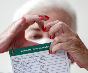 epa08955850 An elderly woman makes the heart sign with her fingers as she holds a certificate after being vaccinated against covid-19 during the immunization process of older adults at long-term care institute for elderly people of Sao Paulo, Brazil, 21 January 2021. Brazil began the vaccination this week throughout its territory with only 6 million doses of Coronavac, which received the go-ahead from the regulatory agency on 17 January, as well as the formula developed by the AstraZeneca laboratory and the University of Oxford.  EPA/SEBASTIAO MOREIRA