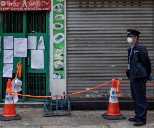 epa08956958 A policeman stands guards next to a cordoned off old tenement building in Jordan district in Hong Kong, China, 22 January 2021. The Hong Kong government will place tens of thousands in lockdown in the districts of Jordan and Yau Ma Tai in a bid to contain the outbreak of coronavirus and COVID-19 disease.  EPA/JEROME FAVRE