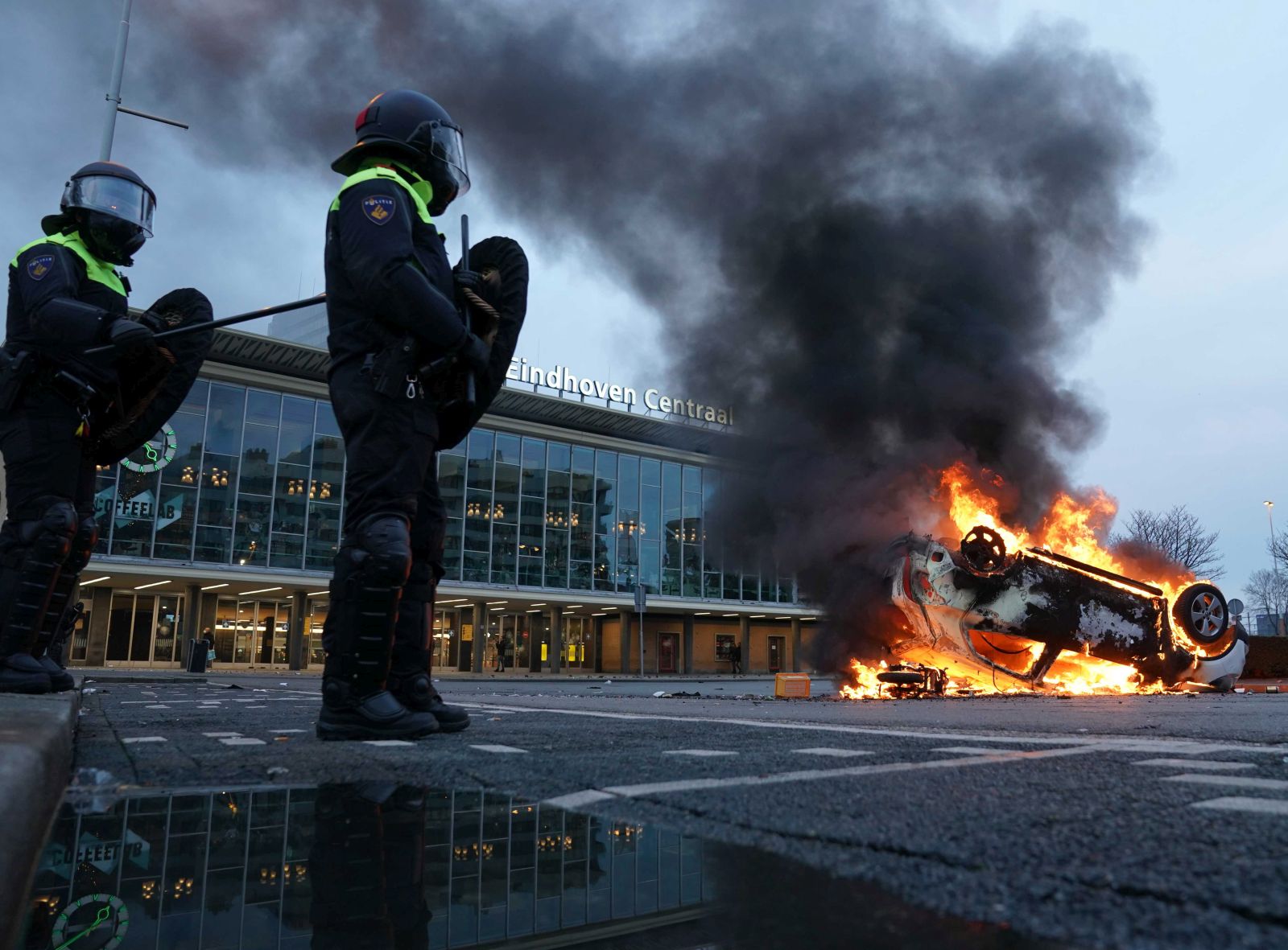 epa08963211 A car has been set on fire in front of the station on the 18 Septemberplein in Eindhoven, the Netherlands, 24 January 2021. Far-right anti-Islam movement Pegida had announced a protest which was banned by the Eindhoven Mayor Jorritsma for fear of disturbances.  EPA/ROB ENGELAAR