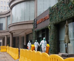Hotel where WHO team members tasked with investigating the origins of the coronavirus (COVID-19) pandemic are quarantined, in Wuhan People in protective suits walk with bins outside the hotel where members of the World Health Organisation (WHO) team tasked with investigating the origins of the coronavirus (COVID-19) pandemic are quarantined, in Wuhan, Hubei province, China January 28, 2021. REUTERS/Thomas Peter THOMAS PETER