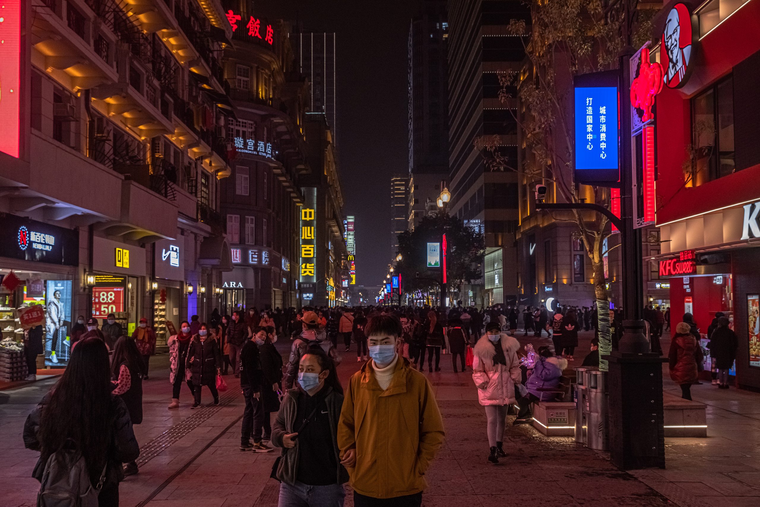 epa08957872 People wearing protective face masks walk in a commercial street, in Wuhan, China, 22 January 2021. The 23 January 2021 marks the one-year anniversary of the start of a strict 76-day lockdown of the Chinese city of Wuhan, where the coronavirus was first discovered before spreading across the world into a deadly global Covid-19 pandemic.  EPA/ROMAN PILIPEY