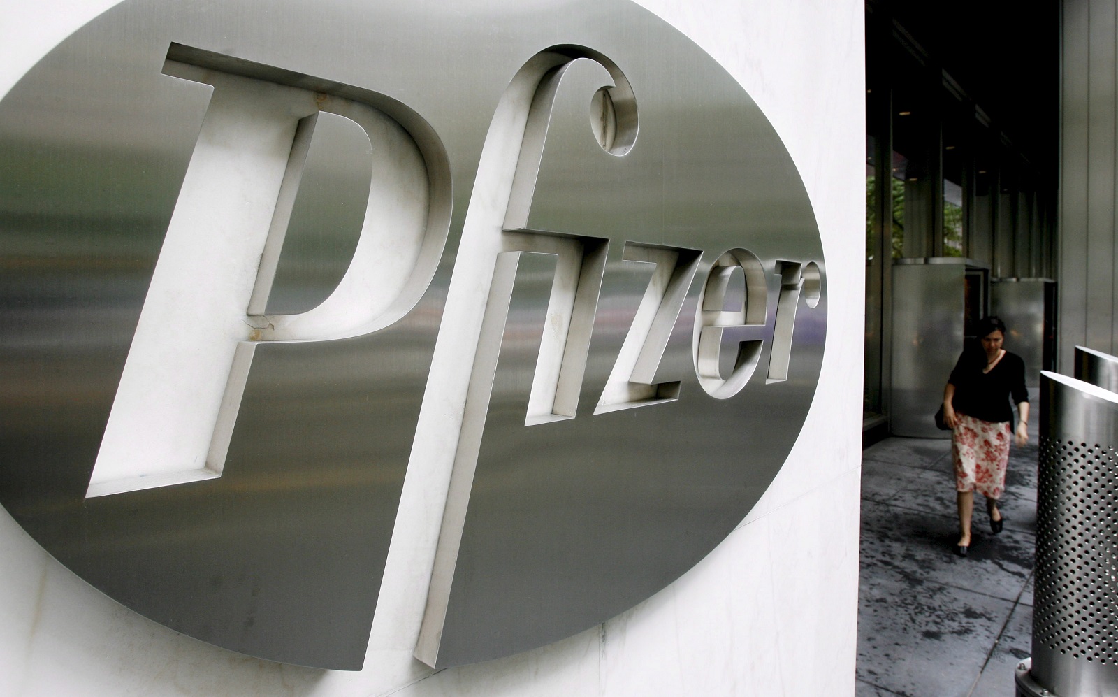 epa08980076 (FILE) - A file image dated 26 June 2006 showing a woman walking past a sign in front of the world headquarters building of Pfizer Inc. in New York, USA (reissued 01 February 2021). Pfizer is due to release its 4th quarter 2020 results on 02 February 2021.  EPA/JUSTIN LANE *** Local Caption *** 52754641