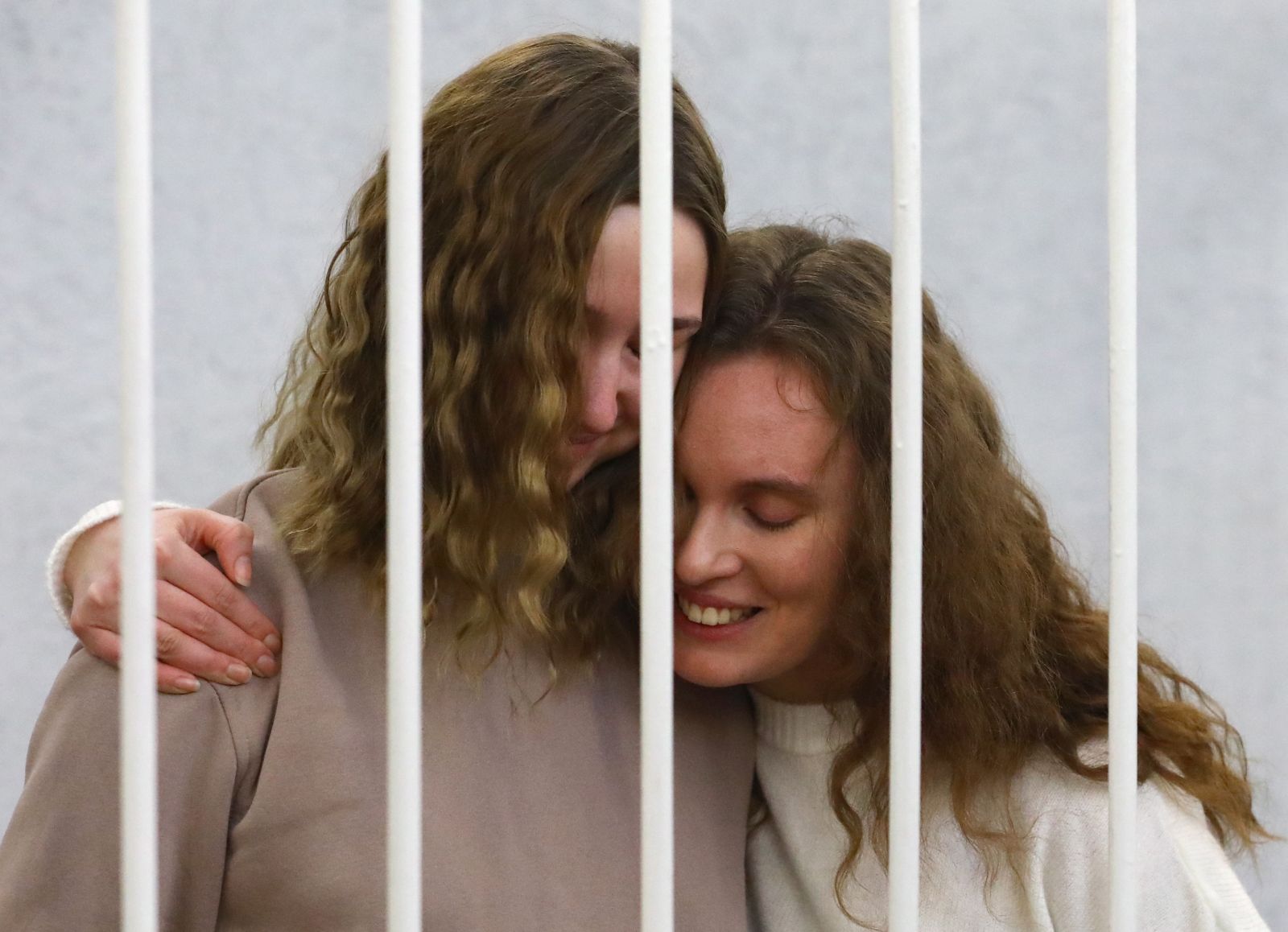 epa08998118 Belsat journalists Katerina Bakhvalova (R) (Andreeva) and Daria Chultsova (L), embrace each other in a cage before the start of a trial in Minsk, Belarus, 09 February 2021. Both journalists were detained in November 2020, when they were reporting on anti-government protests. They face up to three years in prison on charges of organizing and preparing actions that grossly violate public order.  EPA/STRINGER