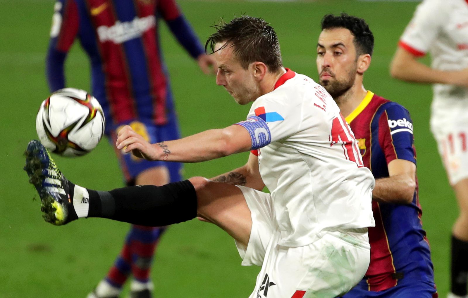 epa09002320 Sevilla's Ivan Rakitic (L) in action against FC Barcelona's Sergio Busquets (R) during the Spanish King's Cup semi final, first leg soccer match between Sevilla FC and FC Barcelona at Ramon Sanchez Pizjuan stadium in Seville, Spain, 10 February 2021.  EPA/Julio Munoz