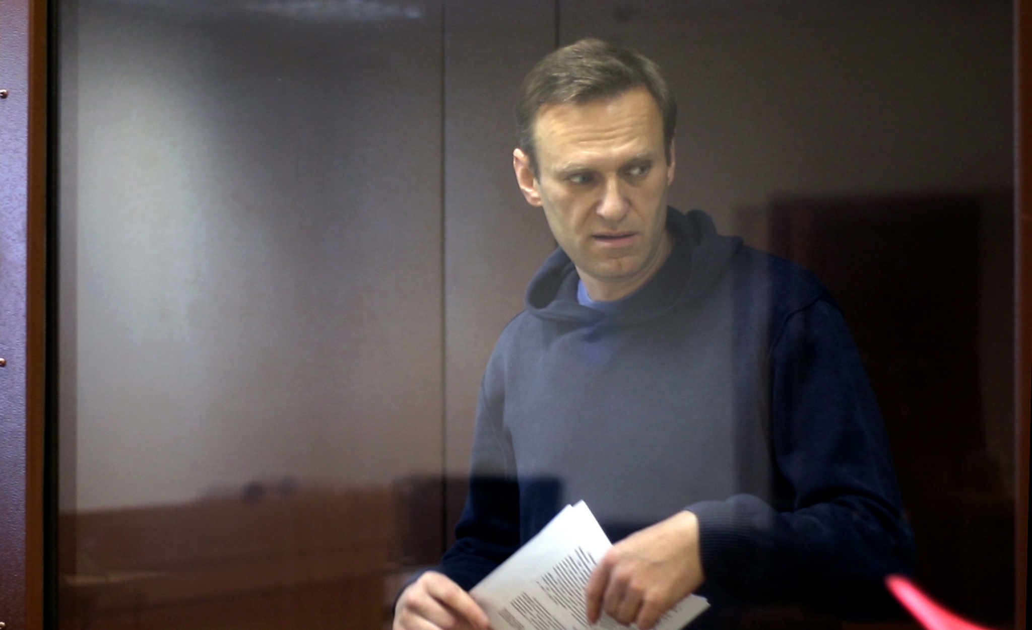 epa09015512 A still image taken from a handout video footage made available by the press service of the Babushkinsky district court shows Russian opposition leader Alexei Navalny inside a glass cage prior to a hearing of a case on slander charges in Moscow, Russia, 16 February 2021. In June 2020 the Russian Investigative Committee opened a criminal case against Alexei Navalny on charges of slander against WWII veteran Ignat Artemenko after Navalny's comment about a video promoting the amendments to the Russian Constitution.  EPA/BABUSHKINSKY DISTRICT COURT PRES -- MANDATORY CREDIT -- BEST QUALITY AVAILABLE -- HANDOUT EDITORIAL USE ONLY/NO SALES