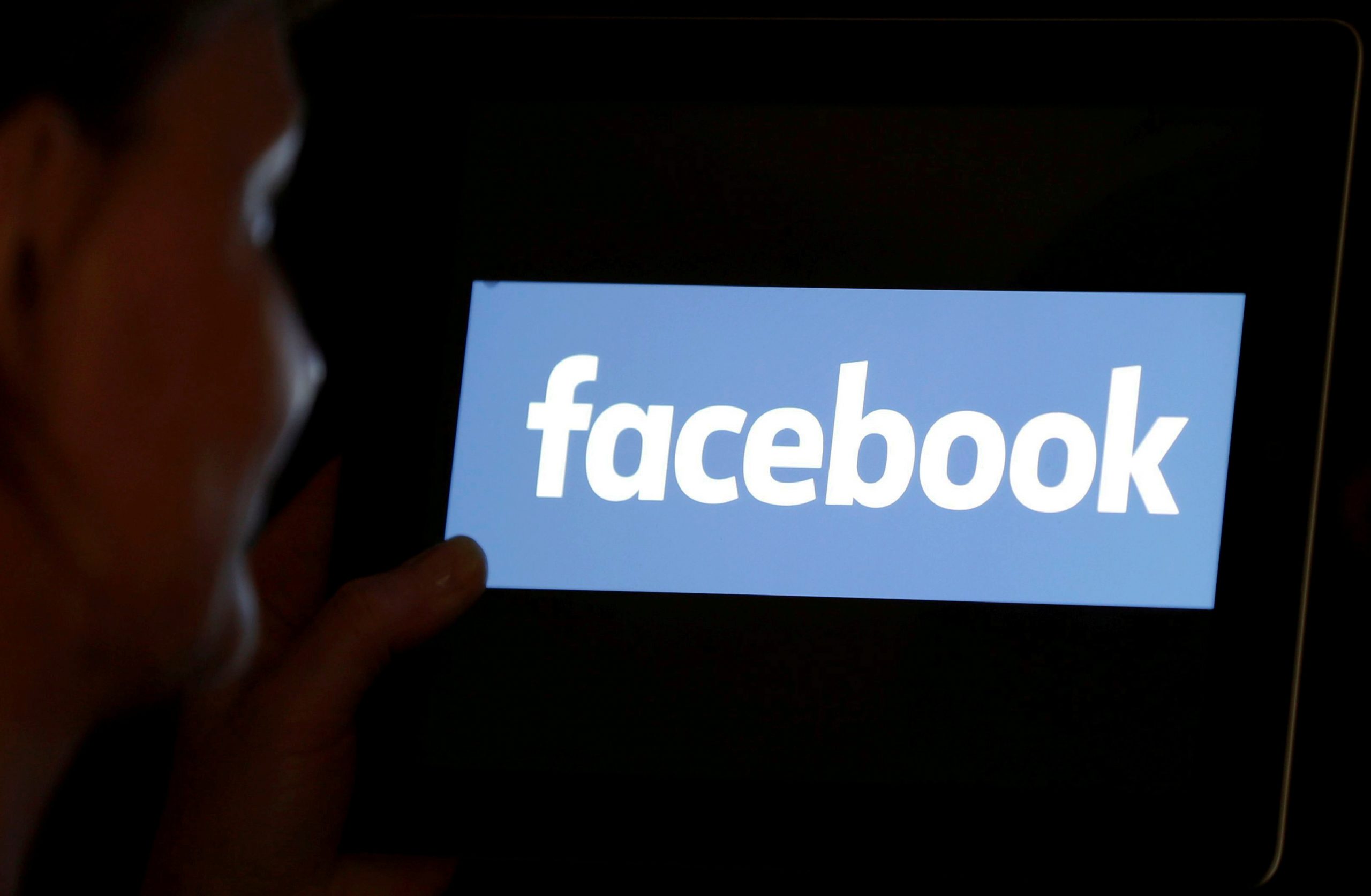 FILE PHOTO: A woman looks at the Facebook logo on an iPad in this photo illustration FILE PHOTO: A woman looks at the Facebook logo on an iPad in this photo illustration taken June 3, 2018. REUTERS/Regis Duvignau/Illustration/File Photo REGIS DUVIGNAU