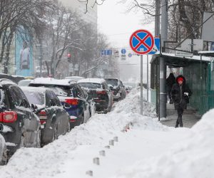 epa09006466 Pedestrians walk past cars parked on a snow-covered street in Kiev, Ukraine, 12 February 2021. Heavy snowfalls and strong frost will hold in Ukraine for the next days as forecasted by weather officials.  EPA/SERGEY DOLZHENKO