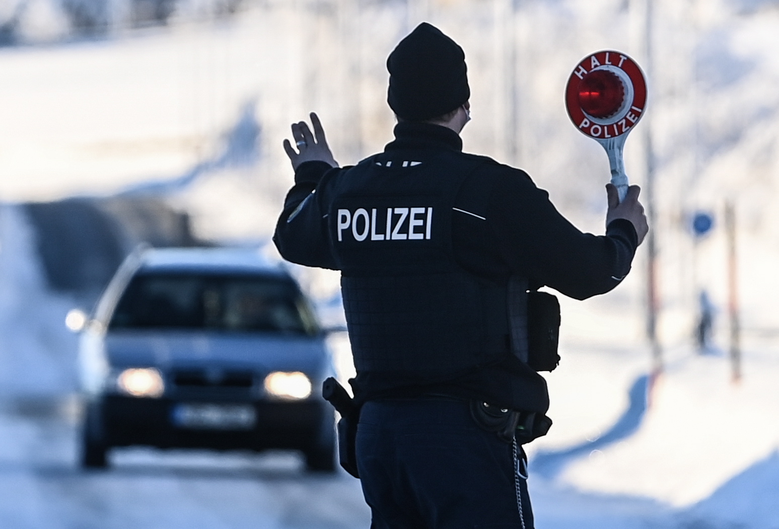 epa09011283 A member of the German Federal Police stops a car at the border crossing in Zinnwald, on the Germany-Czech Republic border, 14 February 2021. Germany reinstated temporary entry bans and border controls from Czech Republic due to growing numbers of coronavirus variant cases in the Czech country. Starting from 14 February, stricter entry rules apply to the German border with the Czech Republic and the Austrian state of Tyrol.  EPA/FILIP SINGER