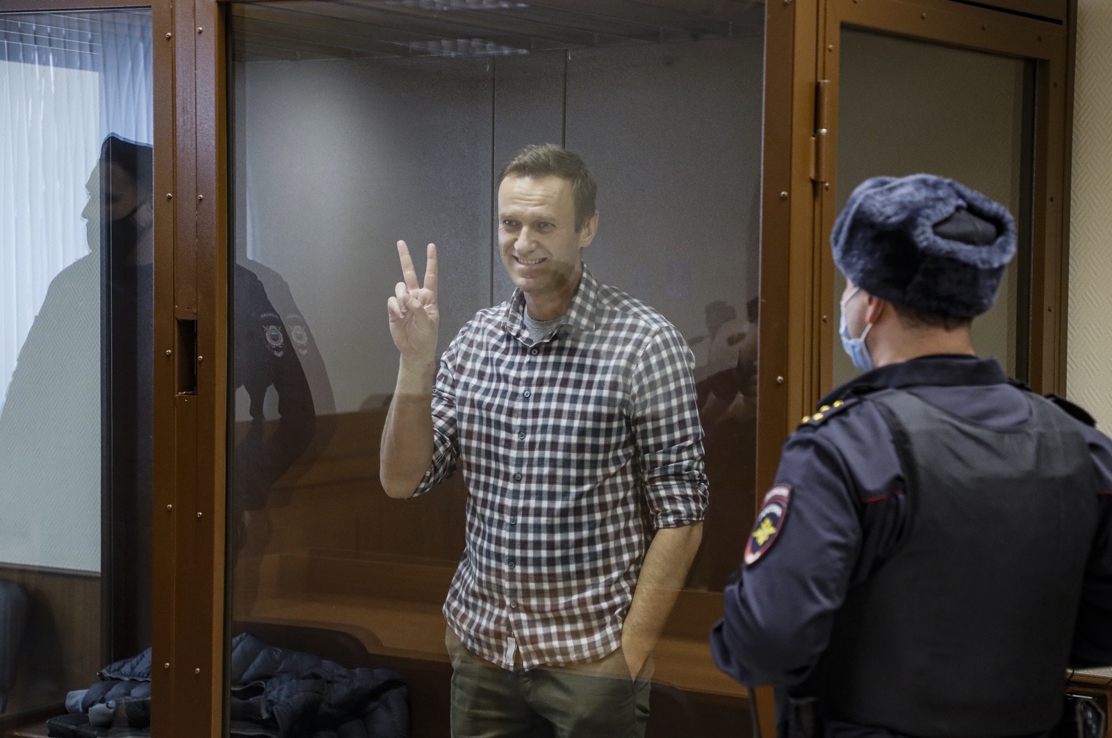 epaselect epa09025242 Russian opposition leader Alexei Navalny gestures inside a glass cage prior to a hearing at the Babushkinsky District Court in Moscow, Russia, 20 February 2021. The Moscow City court will hold a visiting session at the Babushkinsky District Court Building to consider Navalny's lawyers appeal against a court verdict issued on 02 February 2021, to replace the suspended sentence issued to Navalny in the Yves Rocher embezzlement case with an actual term in a penal colony.  EPA/YURI KOCHETKOV MANDATORY CREDIT