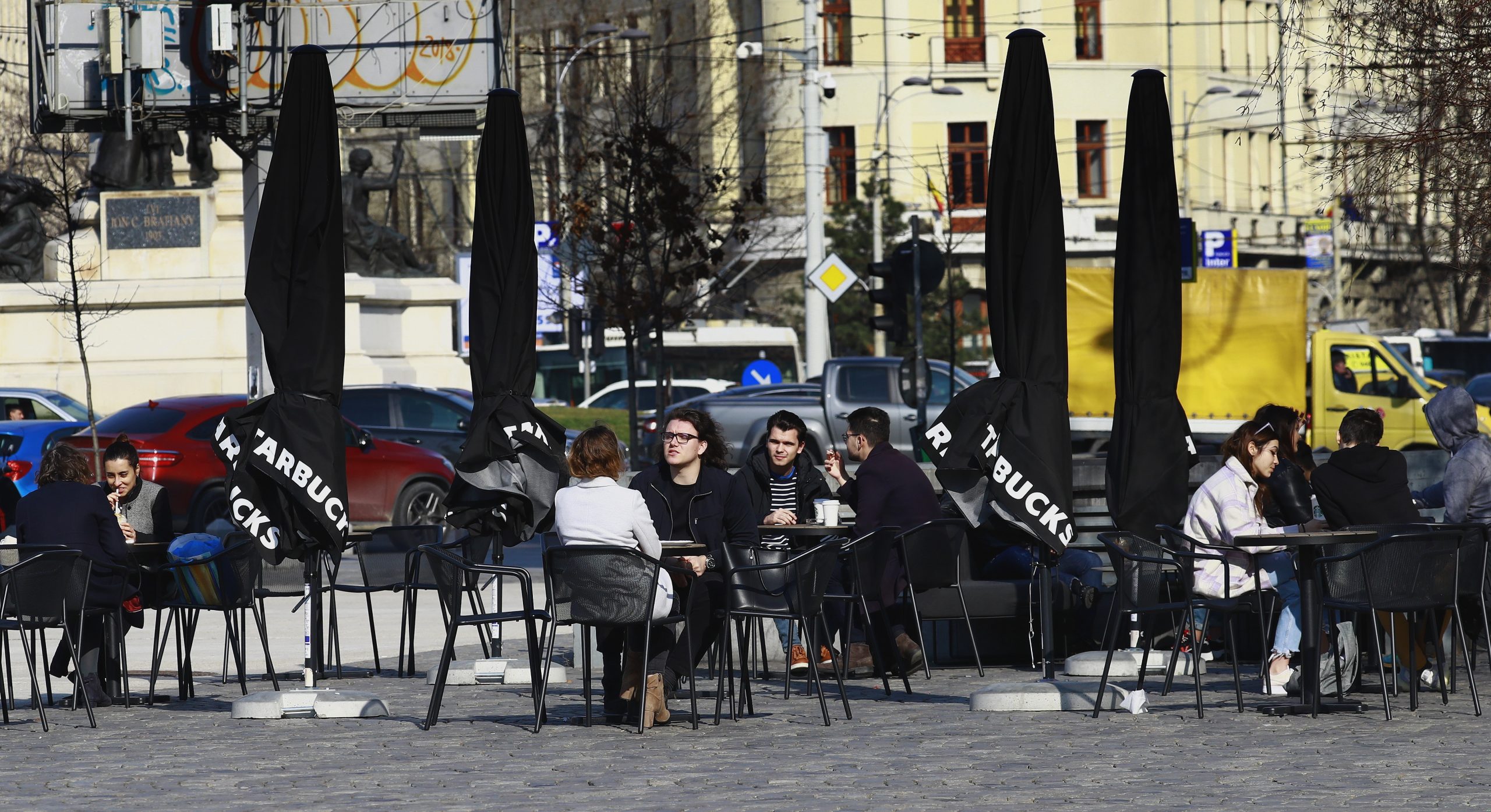 epa09054347 Young Romanian people enjoy a sunny day and their drinks at a terrace at University Plaza, in Bucharest, Romania, 05 March 2021. As the COVID-19 infections number increased recently, Romania's capital is close to the red scenario, in which schools, cinemas and restaurants shall be closed.  EPA/ROBERT GHEMENT