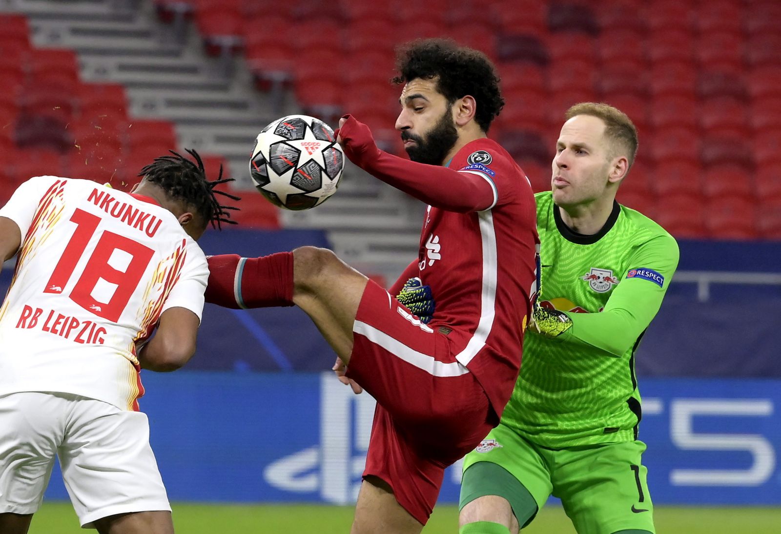 epa09066459 Christopher Nkunku (L) and goalkeeper Peter Gulacsi (R) of RB Leipzig fight for the ball with Mohamed Salah (C) of Liverpool during the UEFA Champions League round of 16, second leg, soccer match between Liverpool FC and RB Leipzig at Puskas Ferenc Arena in Budapest, Hungary, 10 March 2021  EPA/Szilard Koszticsak HUNGARY OUT