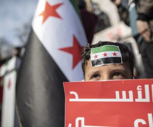 epa09071737 A Syrian child with pre-Baath Syrian flag on his forehead holds a banner during a rally for the 10th anniversary of the Syrian war in Istanbul, Turkey, 13 March 2021. More than 3.6 million Syrians live in Turkey as a result of the decade-long conflict in their home country.  EPA/ERDEM SAHIN