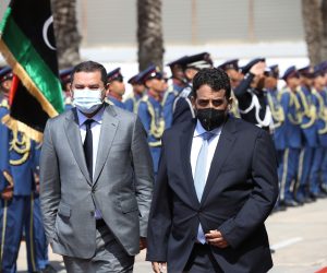 epa09078156 Head of Libya's Presidency Council Mohamed al-Manfi (R) and new interim Prime Minister Abdul Hamid Dbeibah (L) walk together after the formal handover with outgoing GNA head Fayez al-Sarraj (not in picture) at the Presidential Council headquarters in Tripol, Libya, 16 March 2021.  EPA/STR