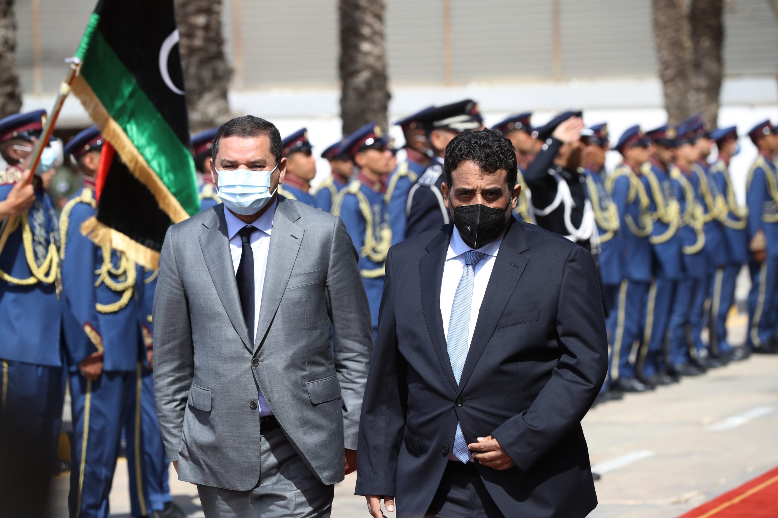 epa09078156 Head of Libya's Presidency Council Mohamed al-Manfi (R) and new interim Prime Minister Abdul Hamid Dbeibah (L) walk together after the formal handover with outgoing GNA head Fayez al-Sarraj (not in picture) at the Presidential Council headquarters in Tripol, Libya, 16 March 2021.  EPA/STR