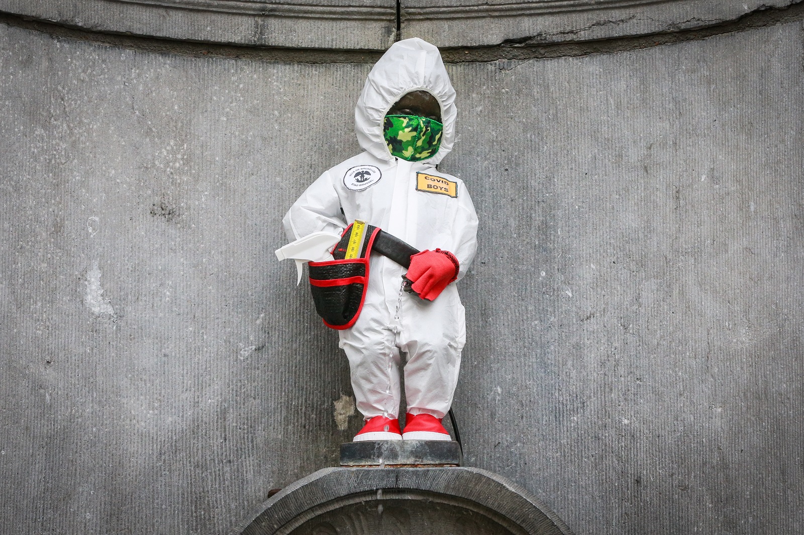 epa09081287 Manneken Pis in costume of "Covid Boys" created in collaboration with the group ''covid Boys'' and the artist Lucas Engels in Brussels, Belgium, 18 March 2021.  EPA/STEPHANIE LECOCQ