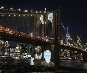 epa09075223 Images of people who died from complications related to the COVID-19 disease are projected on the Brooklyn Bridge during a commemoration ceremony to remember New Yorkers lost during the COVID-19 pandemic in the Brooklyn borough of New York, New York, USA, 14 March 2021. Over 30,000 people have died in New York City as a result of the coronavirus pandemic which began in the United States a year ago this month.  EPA/KEVIN HAGEN / POOL