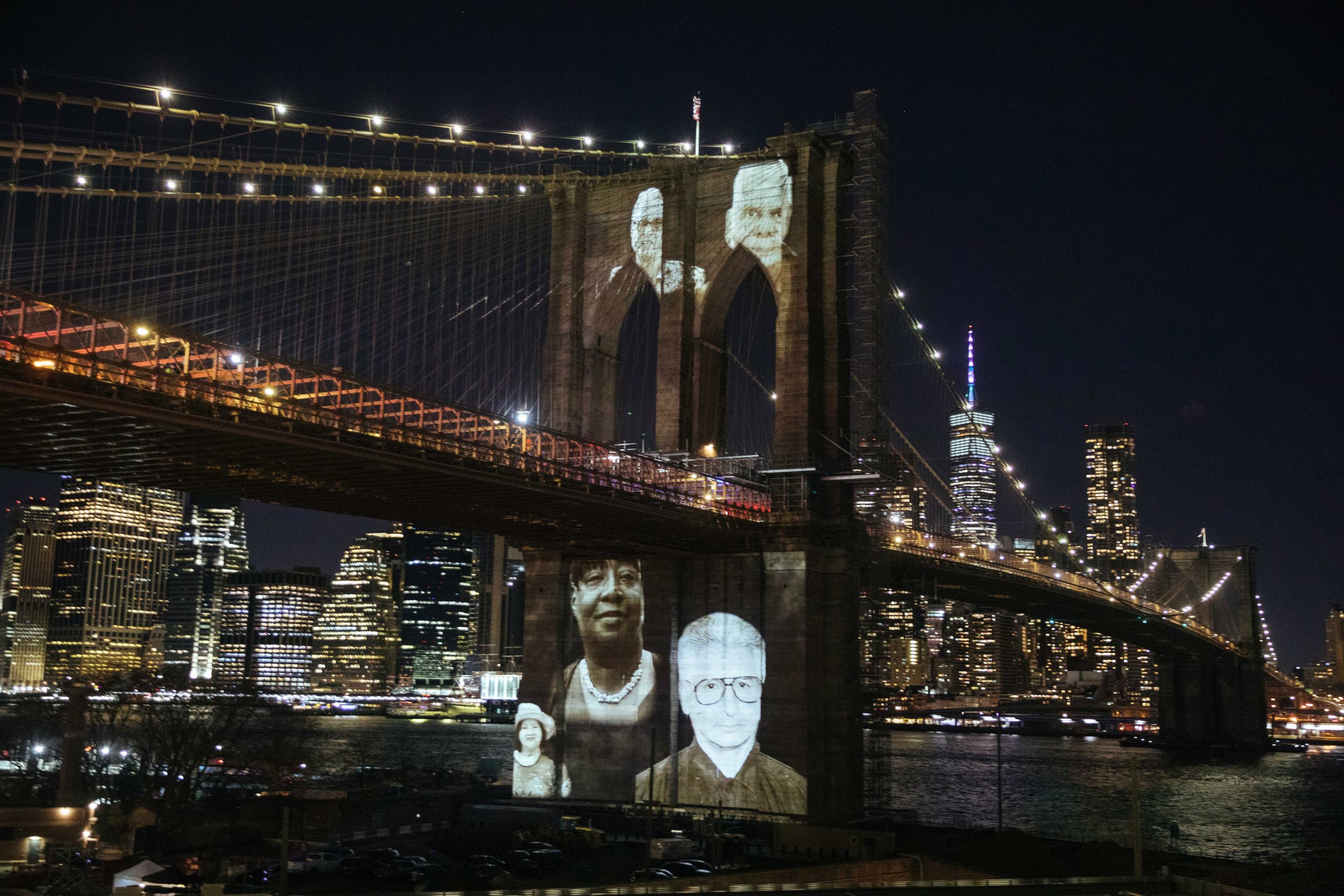 epa09075223 Images of people who died from complications related to the COVID-19 disease are projected on the Brooklyn Bridge during a commemoration ceremony to remember New Yorkers lost during the COVID-19 pandemic in the Brooklyn borough of New York, New York, USA, 14 March 2021. Over 30,000 people have died in New York City as a result of the coronavirus pandemic which began in the United States a year ago this month.  EPA/KEVIN HAGEN / POOL