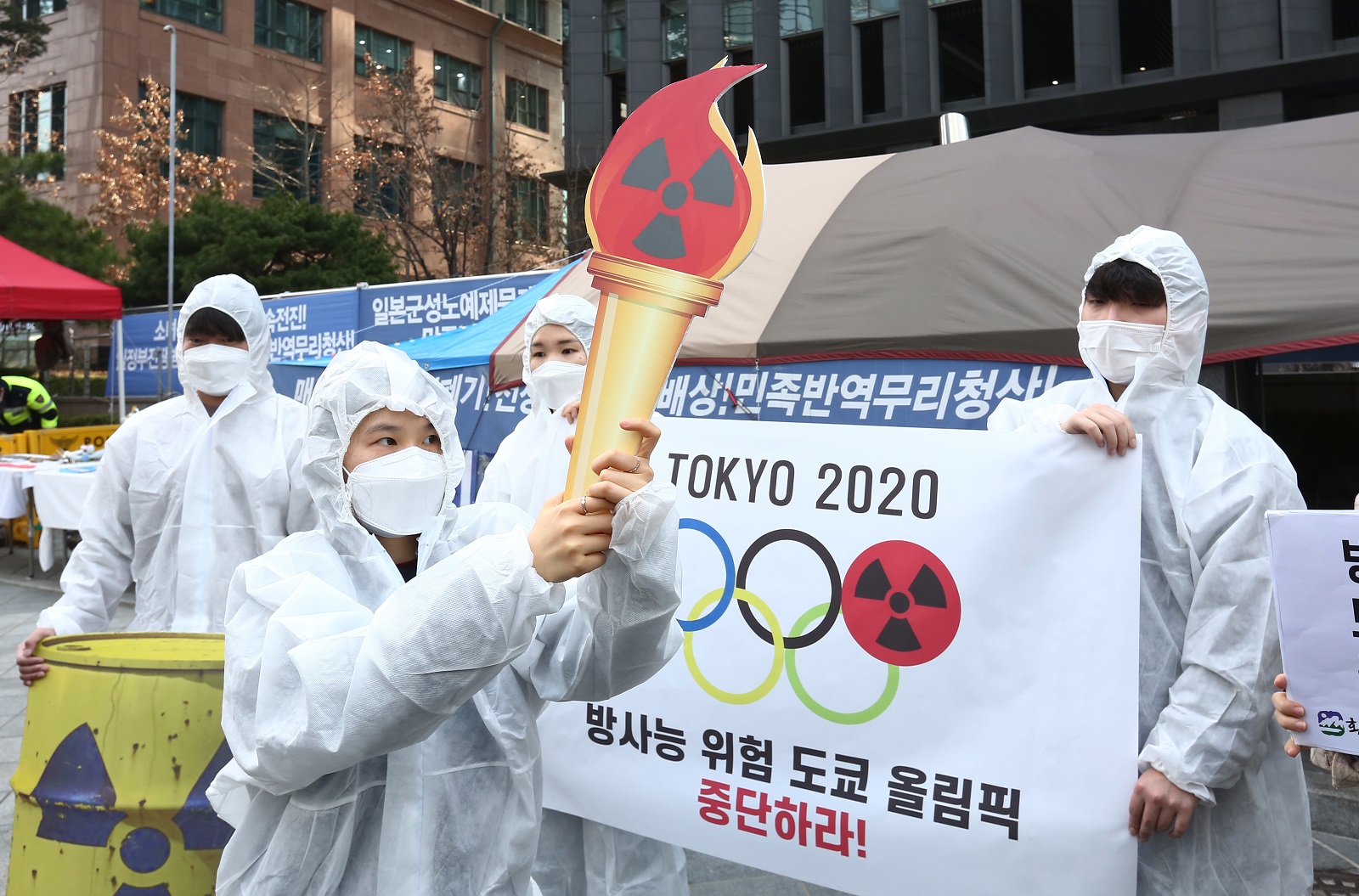 epa09095301 Members of an environmental group wearing mock hazmat suits perform during a protest against Tokyo Olympics near the Japanese embassy in Seoul, South Korea, 25 March 2021. The Summer Olympics in Tokyo is scheduled to start on 23 July and the torch relay event began on 25 March from nuclear disaster-hit Fukushima in Japan.  EPA/JEON HEON-KYUN