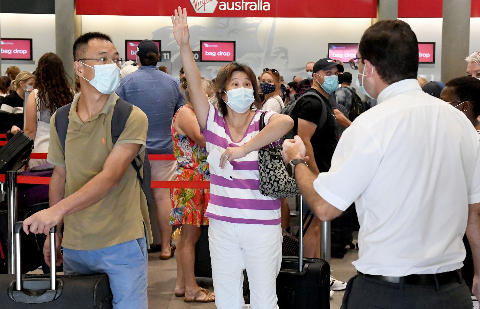 epa09104395 A passenger reacts as she attempts to check in for a flight from the domestic airport in Brisbane, Autralia, 29 March 2021. Greater Brisbane will enter a snap three-day lockdown as its coronavirus outbreak continues to grow.  EPA/DAVE HUNT AUSTRALIA AND NEW ZEALAND OUT