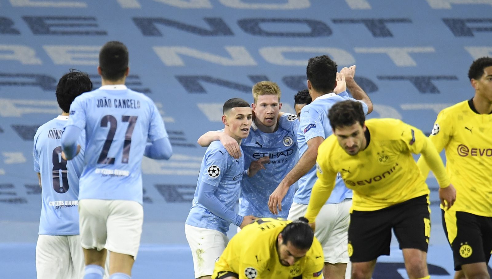 epa09119259 Kevin De Bruyne (back-C) of Manchester City celebrates with teammates after scoring the 1-0 lead as Emre Can (front, bottom) of Dortmund reacts during the UEFA Champions League quarterfinal, 1st leg soccer match between Manchester City and Borussia Dortmund in Manchester, Britain, 06 April 2021.  EPA/PETER POWELL