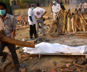 epa09172018 A body is prepared for the last rites at funeral pyres for COVID-19 victims at a makeshift cremation ground in New Delhi, India, 01 May 2021. The country has reported a record number of 400,000 new COVID-19 cases in one day.  EPA/IDREES MOHAMMED